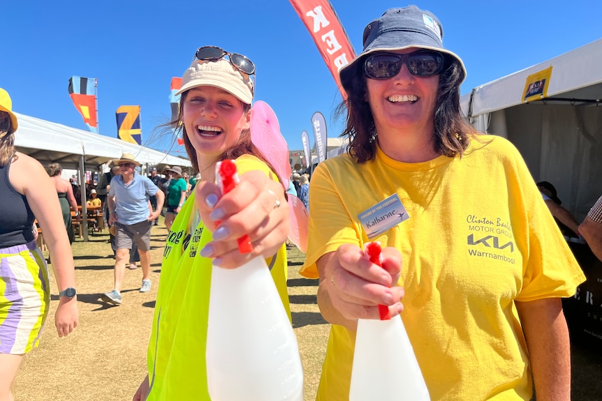Two women holding water spray bottles and smiling.