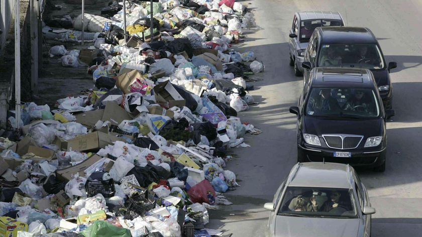 Cars pass mounds of garbage in Naples