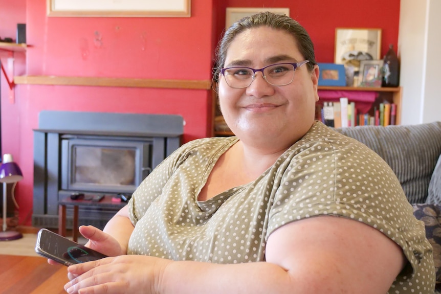 a woman holds a mobile phone while sitting in a lounge room