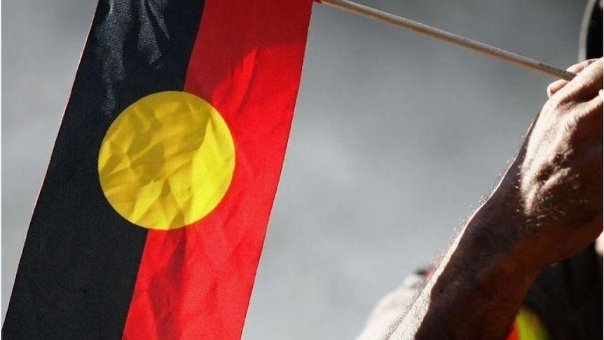 Indigenous Australian holding an Aboriginal flag