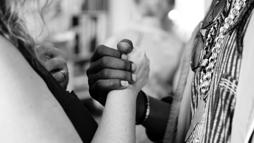 Man and woman of different ethnic groups clasping hands