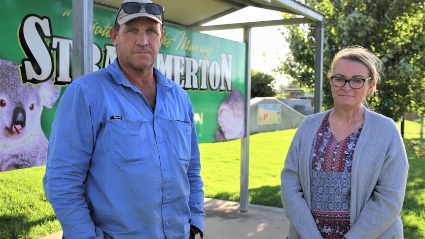 A man and a woman stand in front of sign that says 'welcome to strathmerton'
