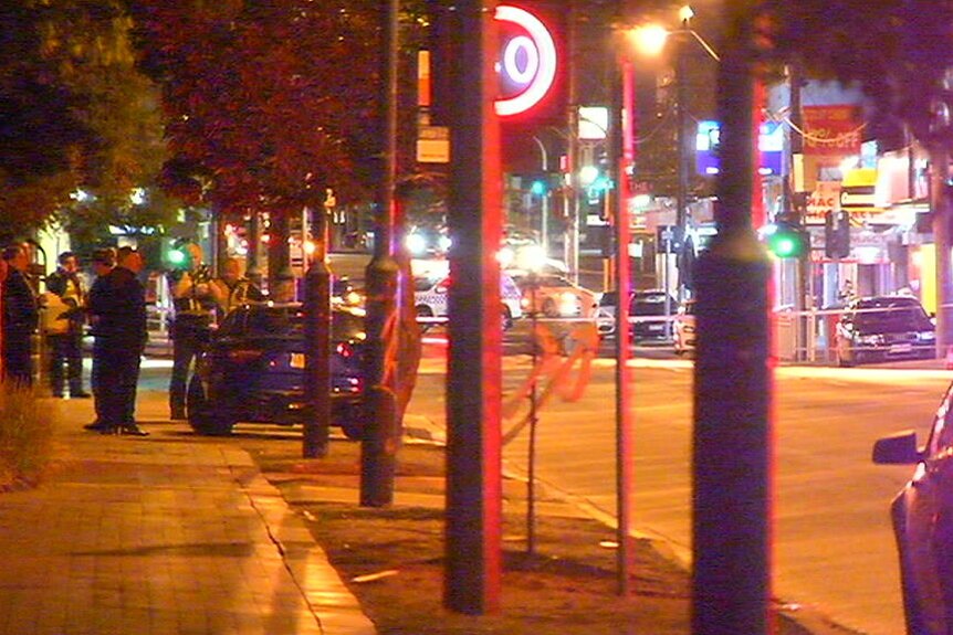 Police officers stand on a street.