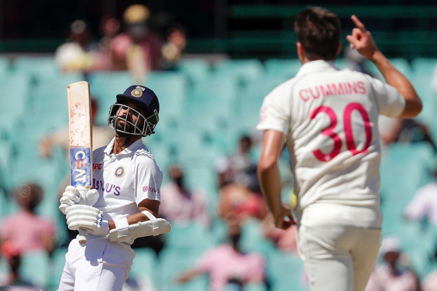 India batsman Ajinkya Rahane throws his head back after being bowled by Pat Cummins, who is celebrating in the foreground.