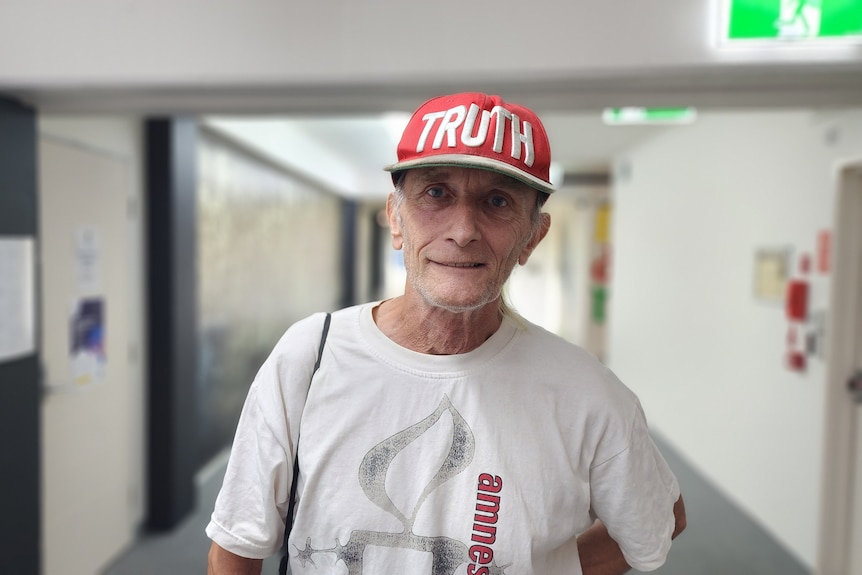 man looking directly at camera wearing red cap that reads "TRUTH" 