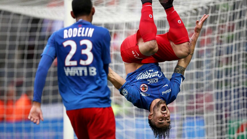 SM Caen forward Andy Delort is captured upside down as he does a backflip after scoring a goal.