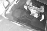 A surveillance image of a driver using a phone.