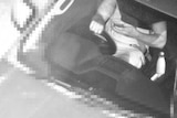 A surveillance image of a driver using a phone.