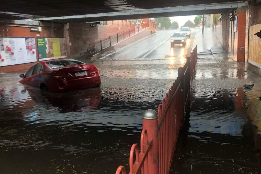 Car drowning in water under bridge.