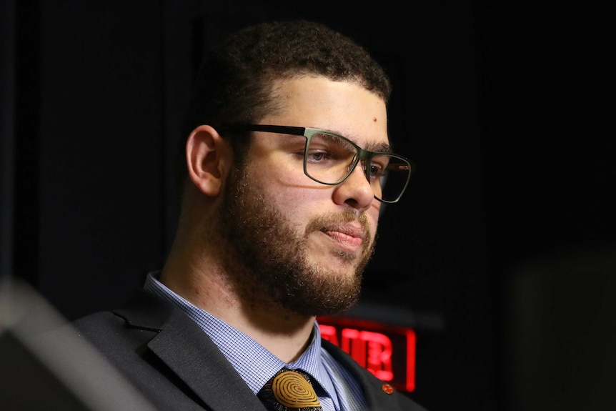 A close-up shows Jordon Steele-John's face as he purses his lips and looks down. There is a red 'on air' light behind him.