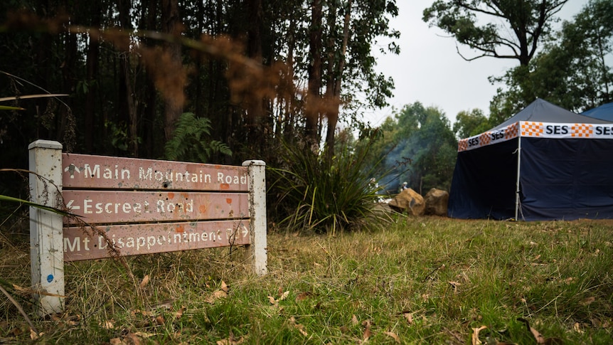 A sign at Mount Disappointment surrounded by grass, trees and an SES tent.