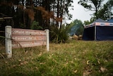 A sign at Mount Disappointment surrounded by grass, trees and an SES tent.