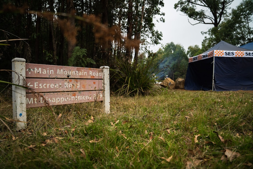 A sign at Mount Disappointment surrounded by grass, trees and an SES tent.