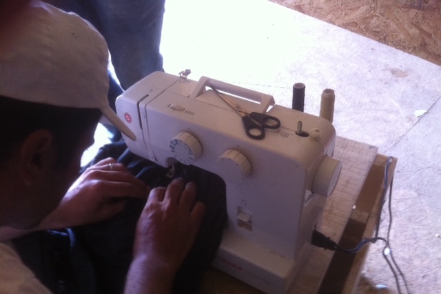 An asylum seeker at the Idomeni camp uses a sewing machine at the information tent