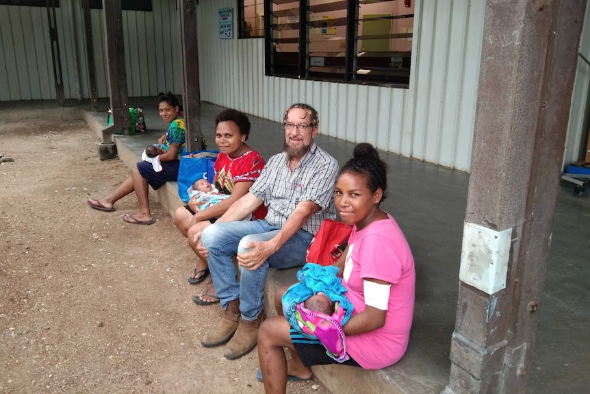 Caucasian man sitting down with Papua New Guinean local women.