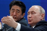 Shinzo Abe looks unimpressed as he listens to Putin talk at a forum.