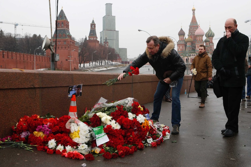 People lay flowers at the site where Russian opposition leader Boris Nemtsov was killed, Kremlin in the background