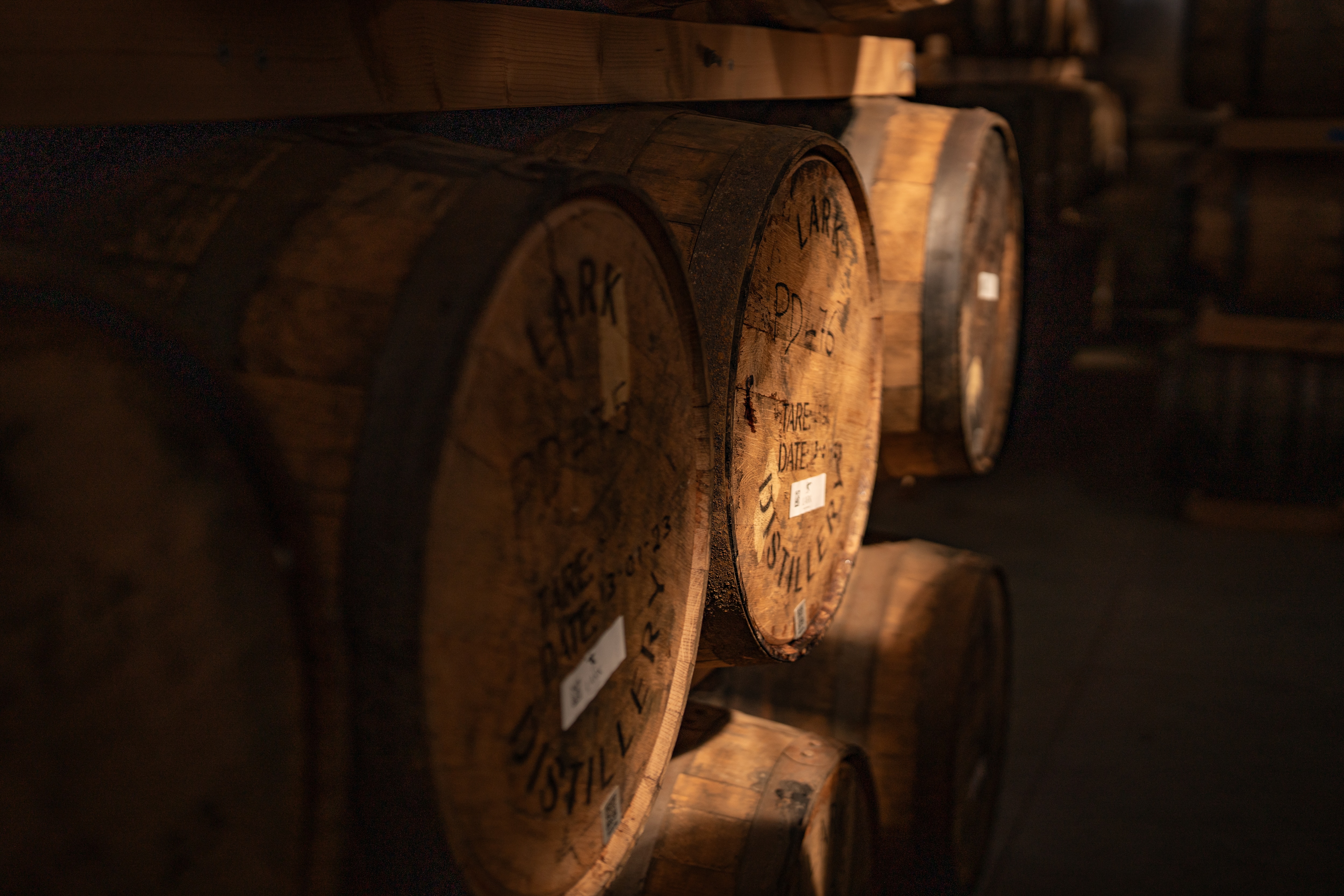Dusty barrels and a warm coloured copper still in large shed