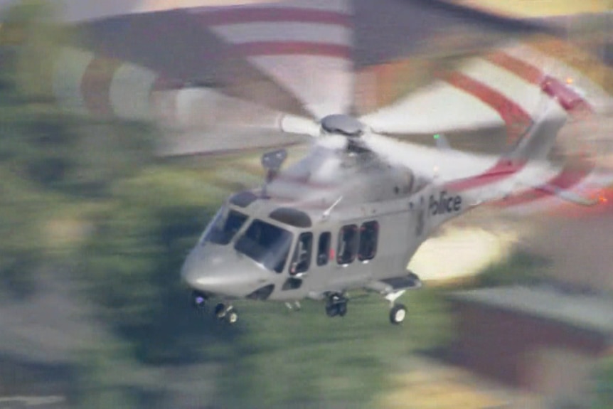A helicopter in the air, the word 'police' visible on its tail.
