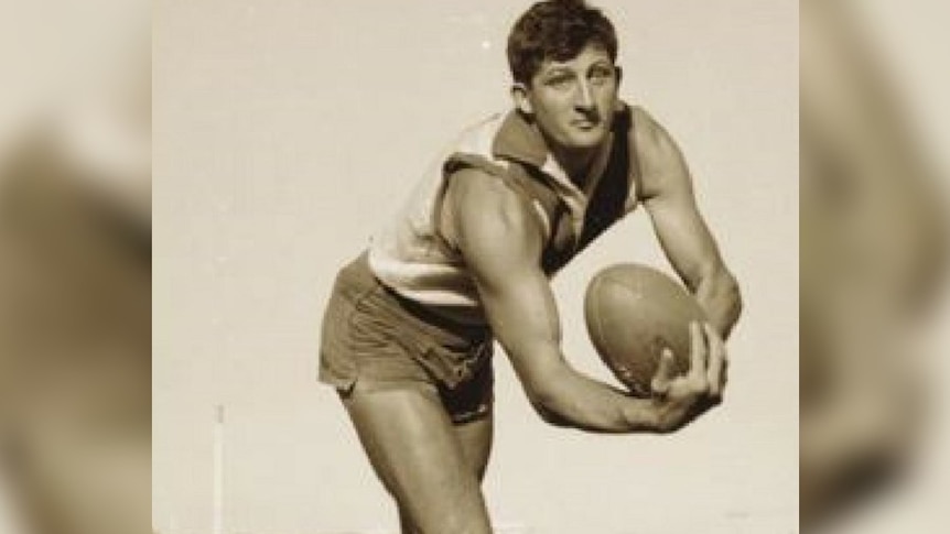A man named John Todd handballs an Australian rules football