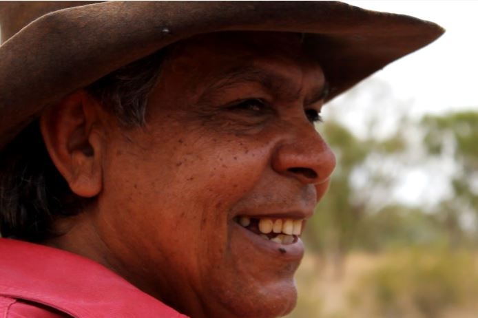 Indigenous man Peter Parlow smiles as he looks into the distance.
