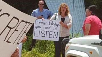 Tweed Mayor Katie Milne holds a sign at a protest against the new Tweed Valley Hospital site.