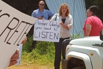 Tweed Mayor Katie Milne holds a sign at a protest against the new Tweed Valley Hospital site.