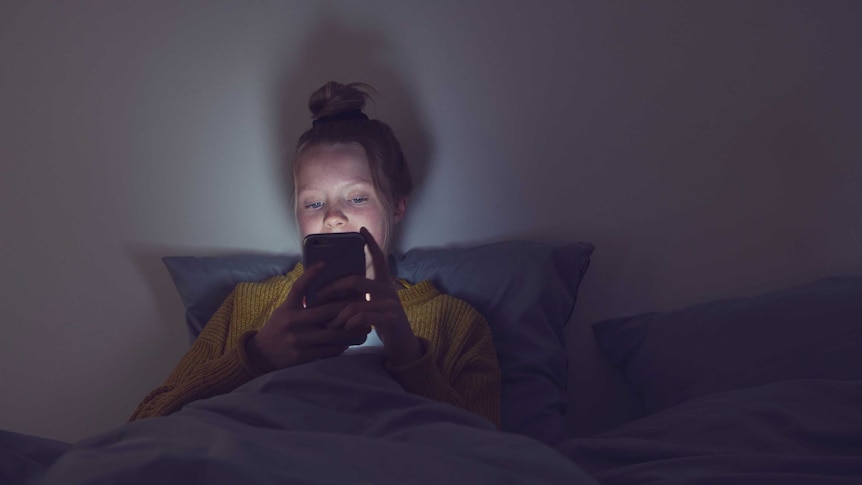 Teenage girl in bed looking at phone