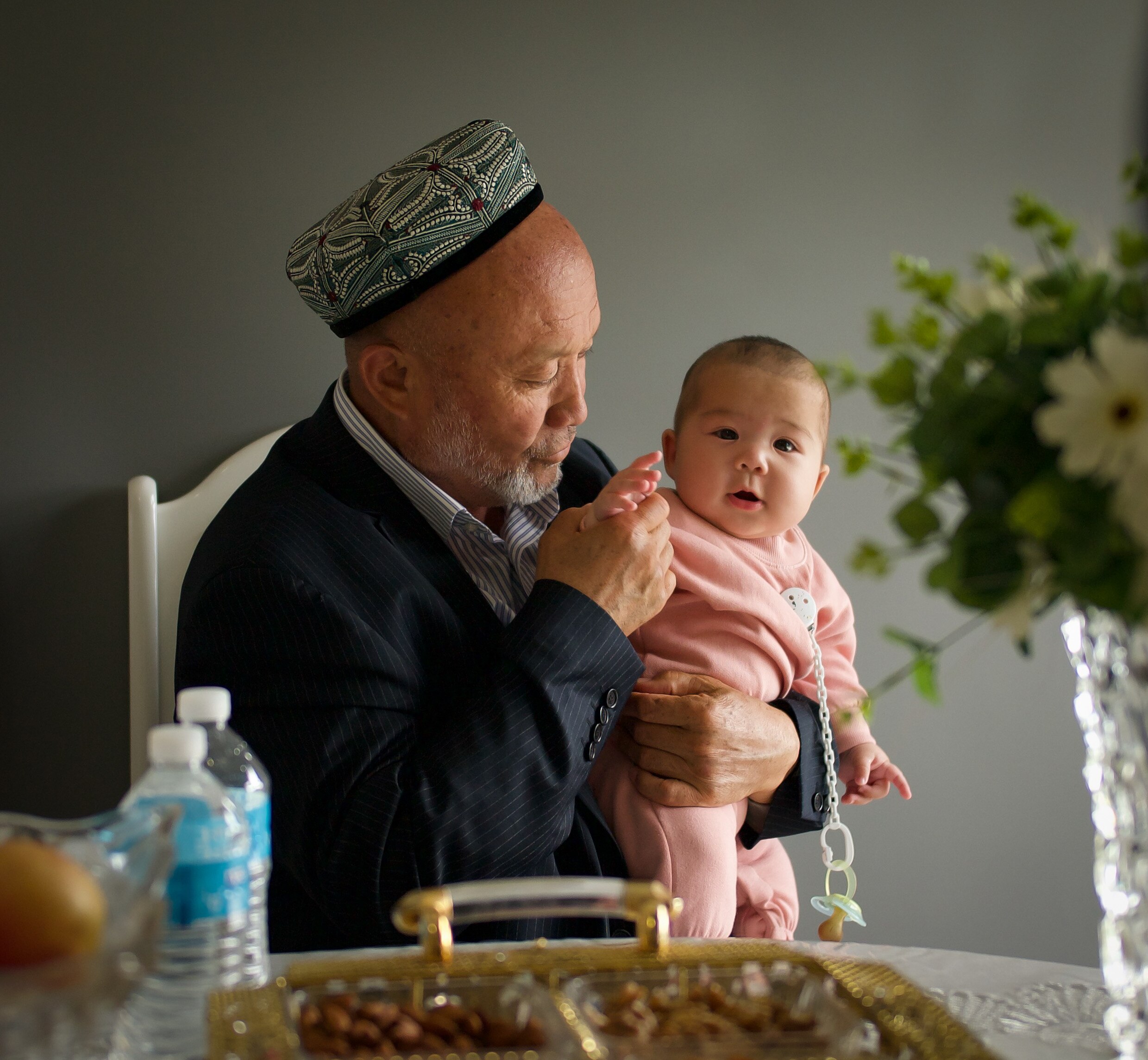 An older man holds a young baby.