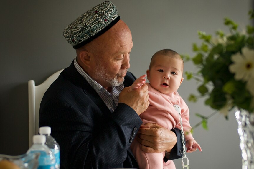 An older man holds a young baby.
