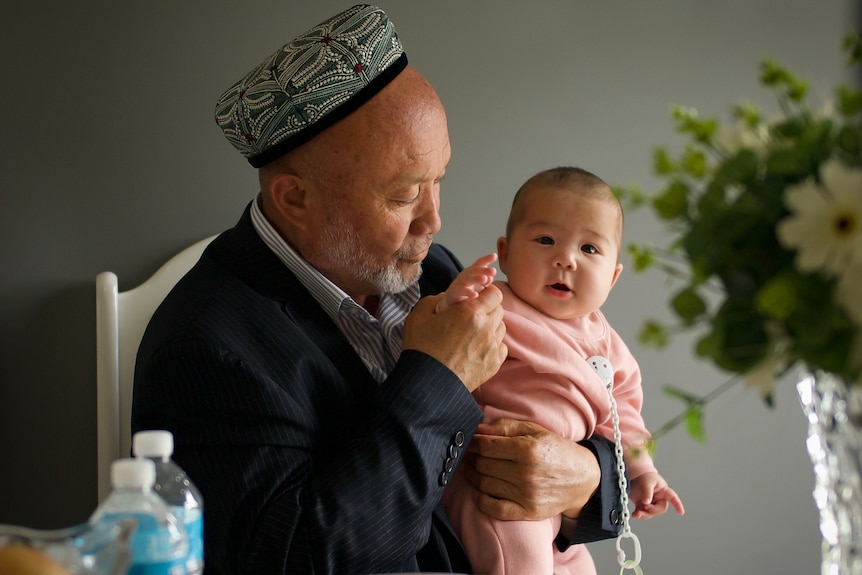 An older man holds a young baby.