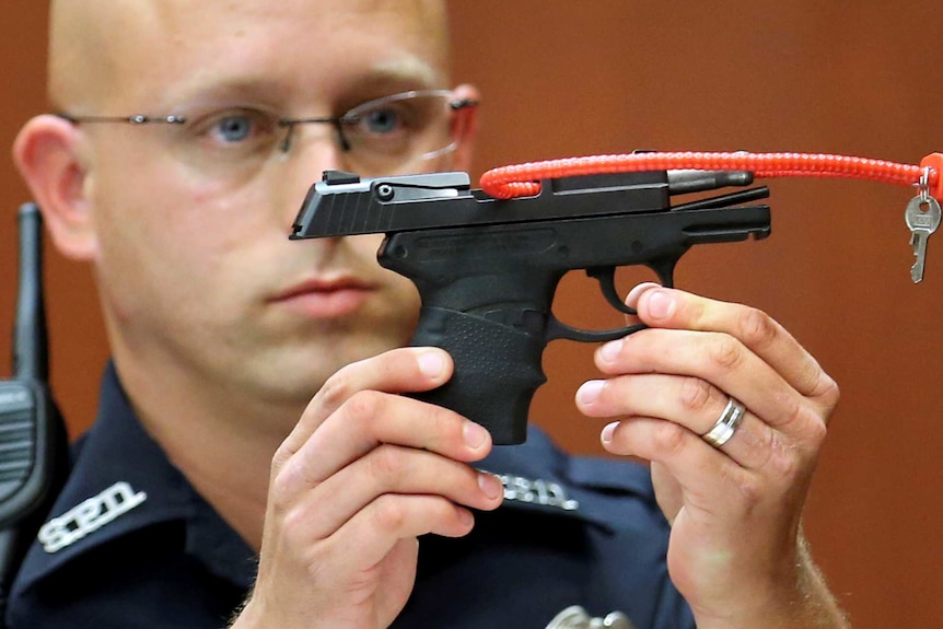 A police officer holds up the gun used to kill Trayvon Martin.