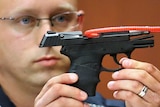A police officer holds up the gun used to kill Trayvon Martin.