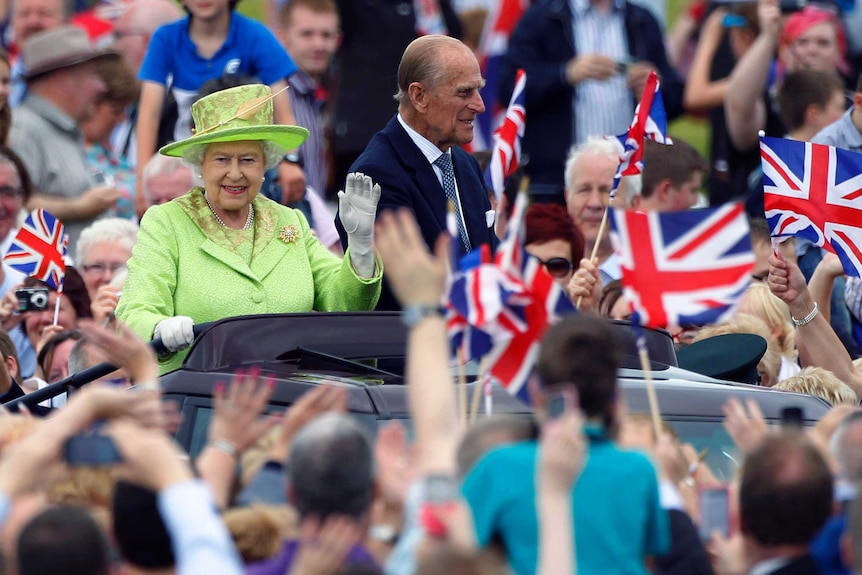Queen Elizabeth II waves as she and Prince Philip drive through a crowd of fans in 2012.