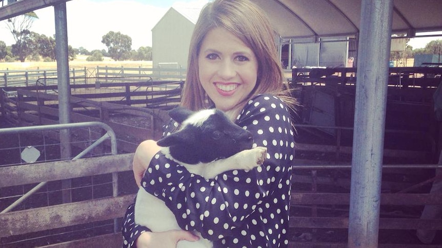 ABC reporter Stephanie Dalzell holding a lamb on a farm in Western Australia.