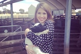 ABC reporter Stephanie Dalzell holding a lamb on a farm in Western Australia.