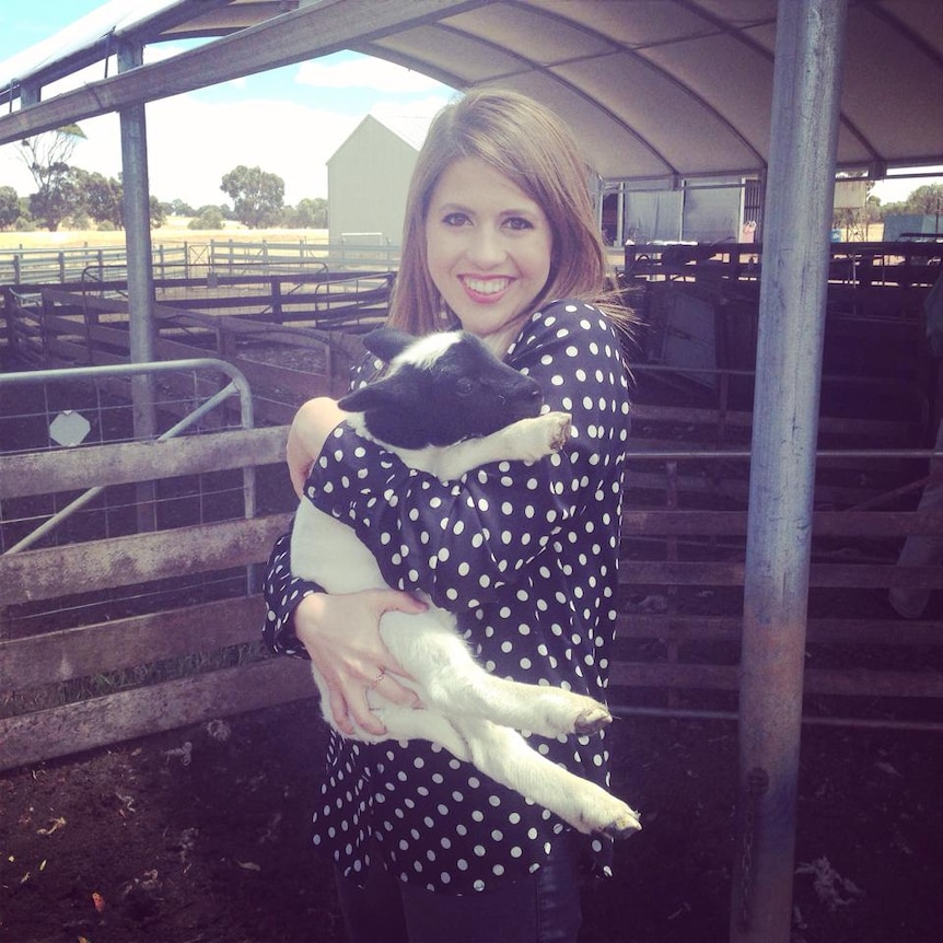 ABC reporter Stephanie Dalzell holding a lamb on a farm in Western Australia.