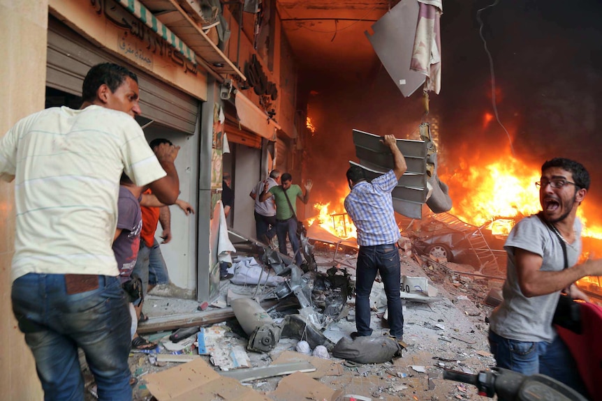 Lebanese civilians and emergency personnel gather at the site of a car bomb in Beirut.