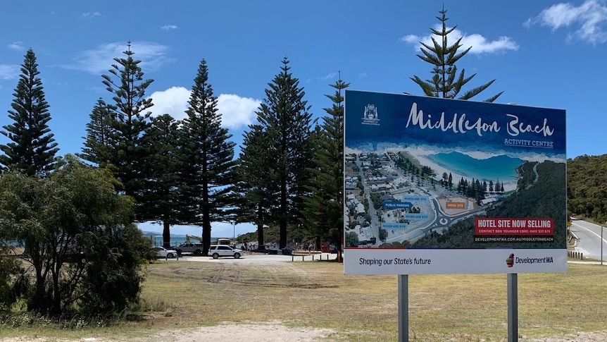A sign showing Middleton Beach with a car park and the beach in the background