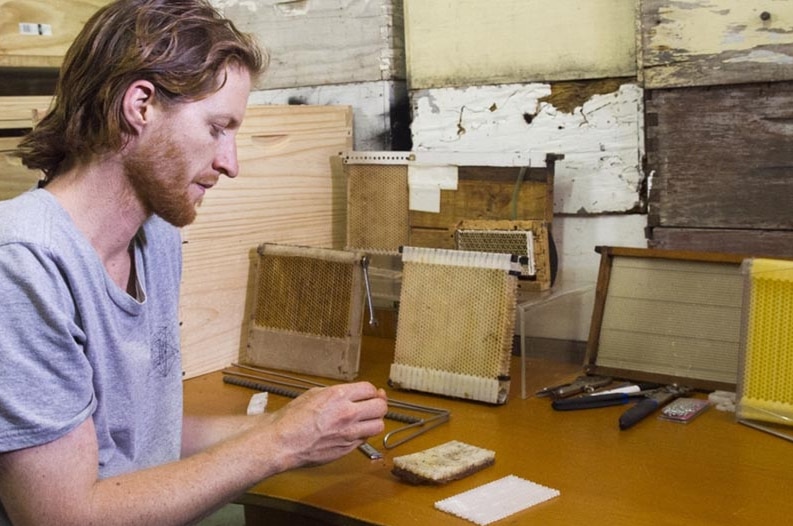 Flow Hive creator Cedar Anderson in a rustic shed in Byron Bay, tinkering with some tools.