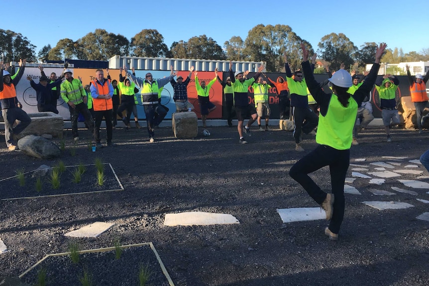 High-vis clad workers do yoga.
