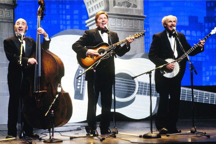 Three musicians perform on stage in a scene from a film.