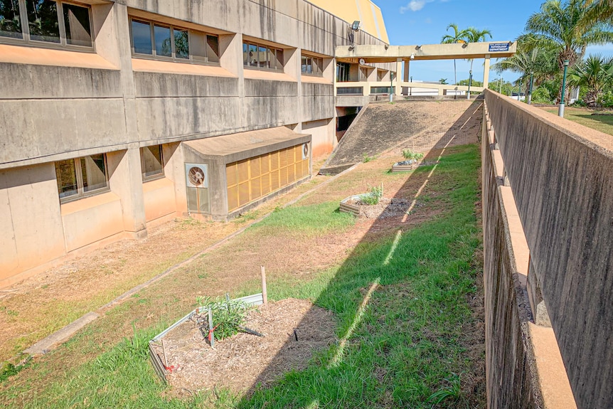 A trench surrounded by a concrete building and a concrete wall.