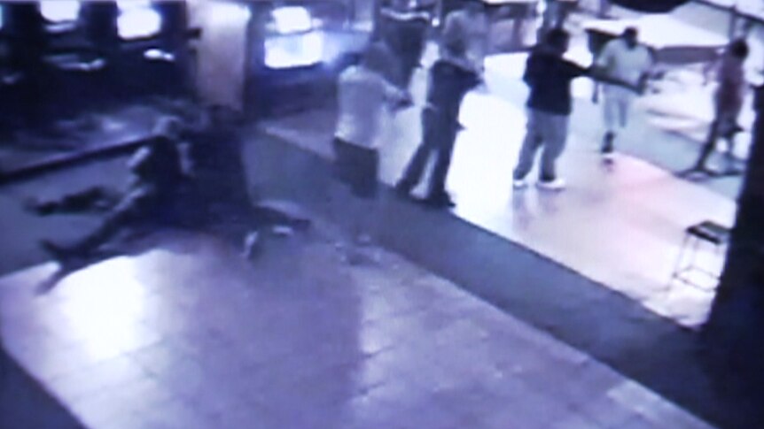 CCTV image shows people on the floor and a person on a phone. 