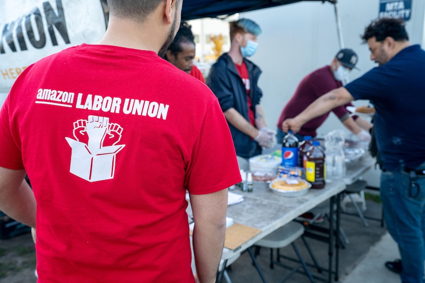 A man wear a red t-shirt with the words Amazon Labor Union written on it