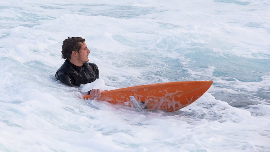 Harry Holmer-Cross on his surfboard in white water.