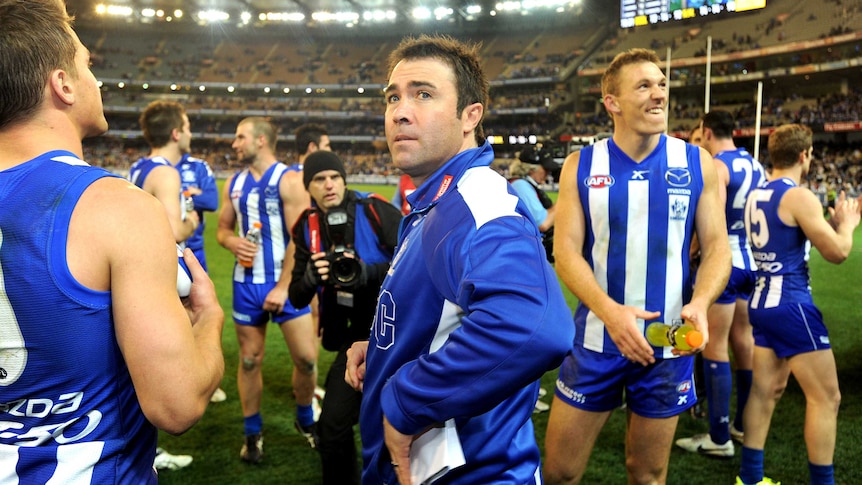 North Melbourne coach Brad Scott celebrates with players after finals win over Geelong at the MCG.