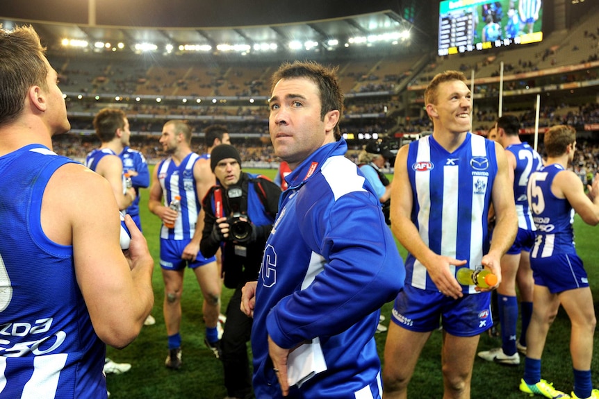 Kangaroos coach Brad Scott celebrates with his players after the Roos beat Geelong at the MCG.