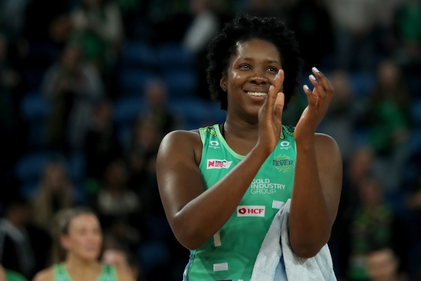 Jamaican player claps hands together after game with smile on face to thank fans