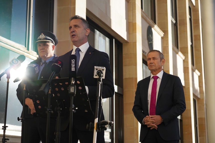 Paul Papalia speaks into microphones at a media conference outside parliament, flanked by Col Blanch and Roger Cook.